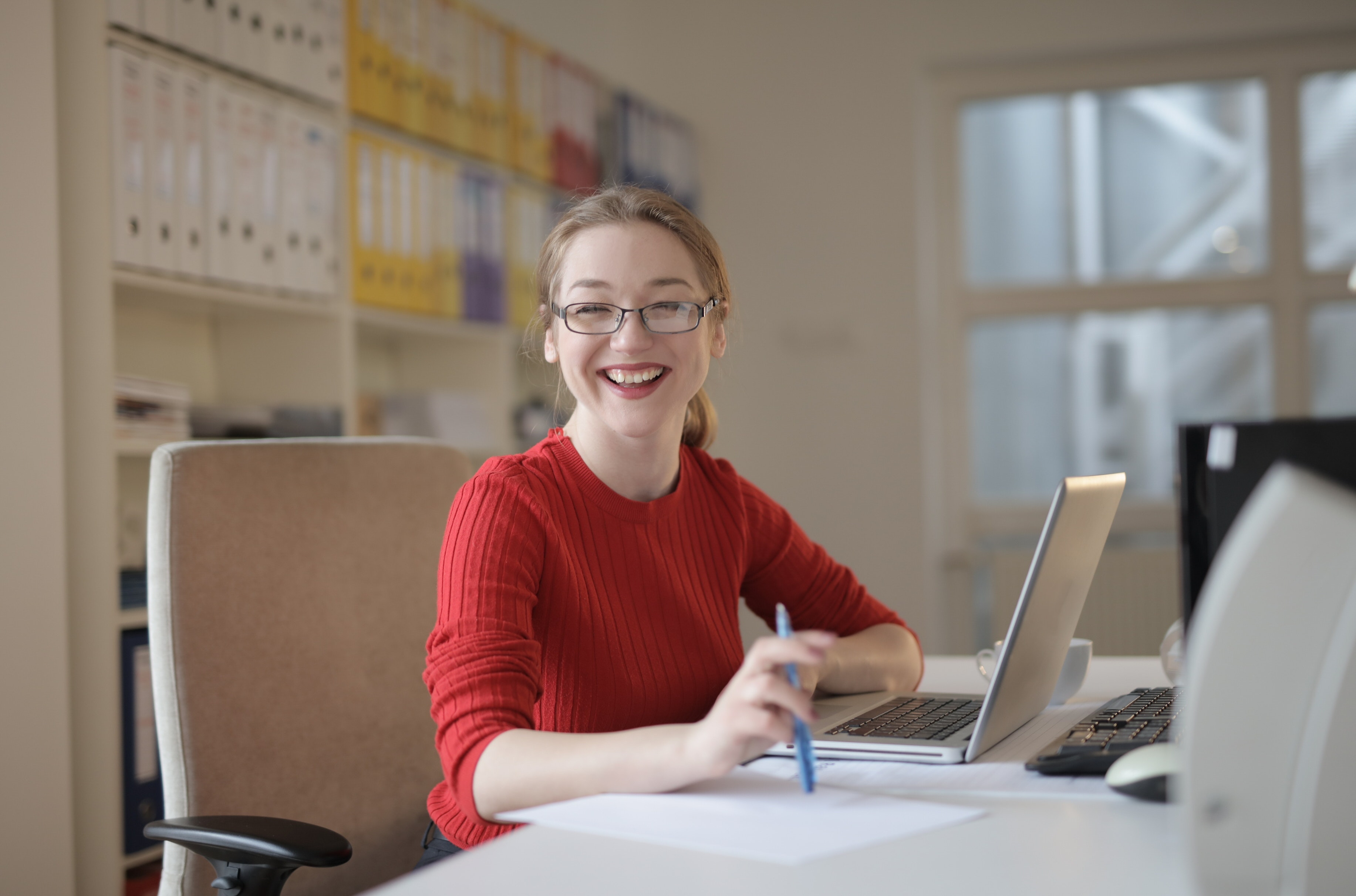 A white woman in an office smiling at the camera in front of her laptop. Office at Accurate Title Solutions.