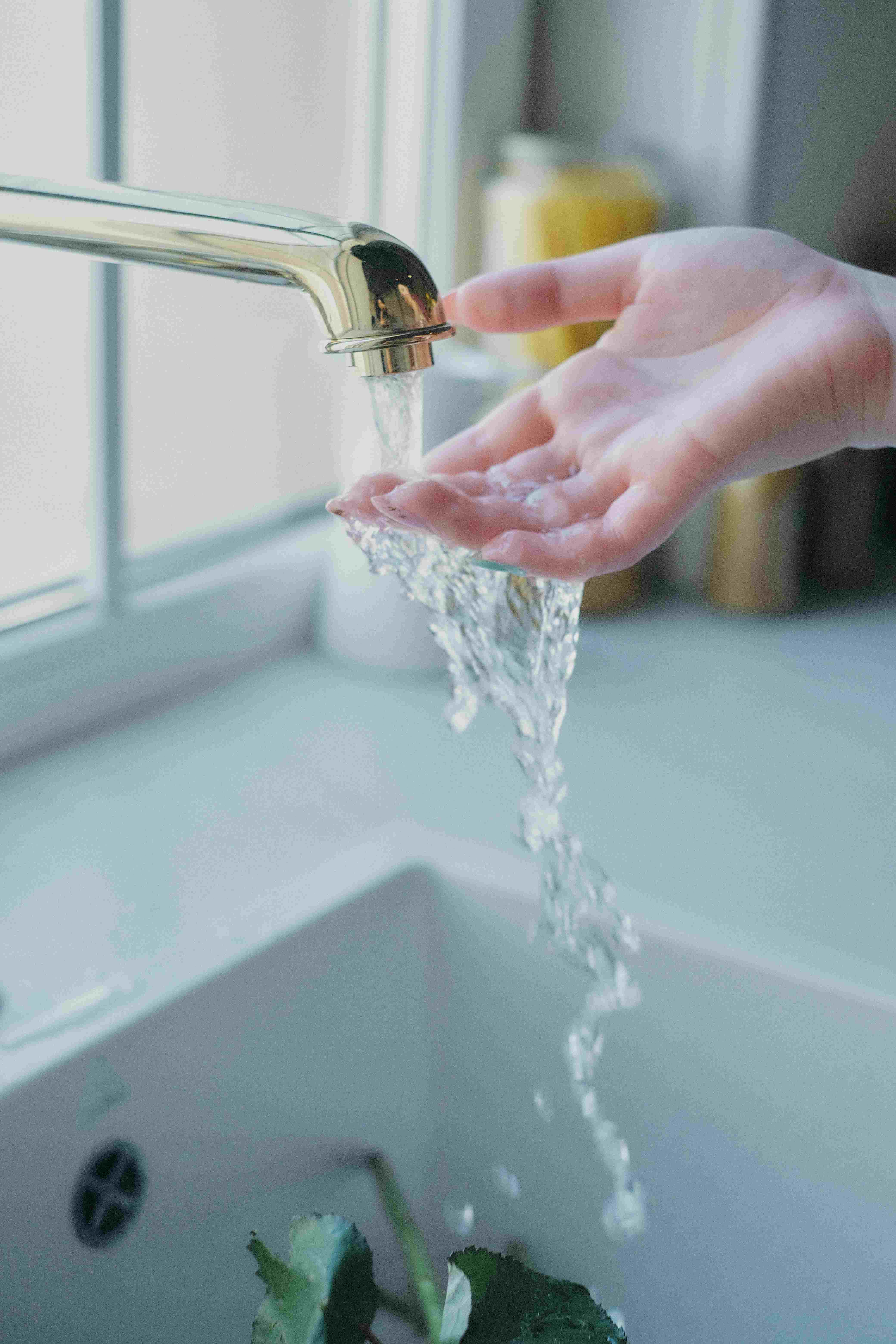 Water running through a woman's hand at a sink. Utility Connect feature, complimentary solutions provided by Accurate Title Services in Madisonville, Louisiana.
